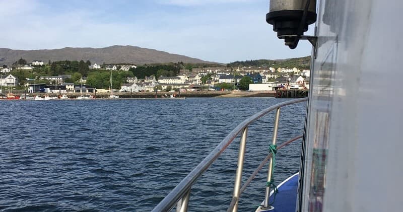Coastal village from boat railing, calm harbor approach tour