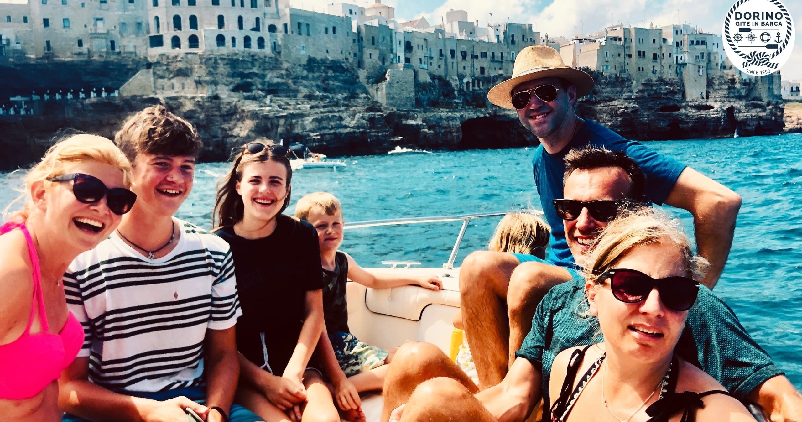 Group of friends on a sightseeing boat near rocky coastal town