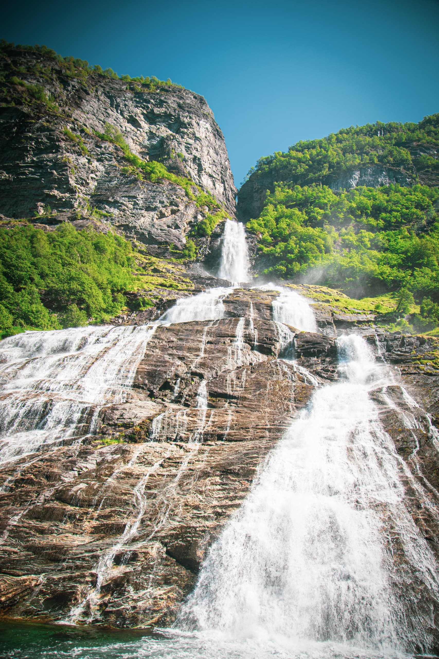Towering mountain waterfall cascading through lush valley, Norway