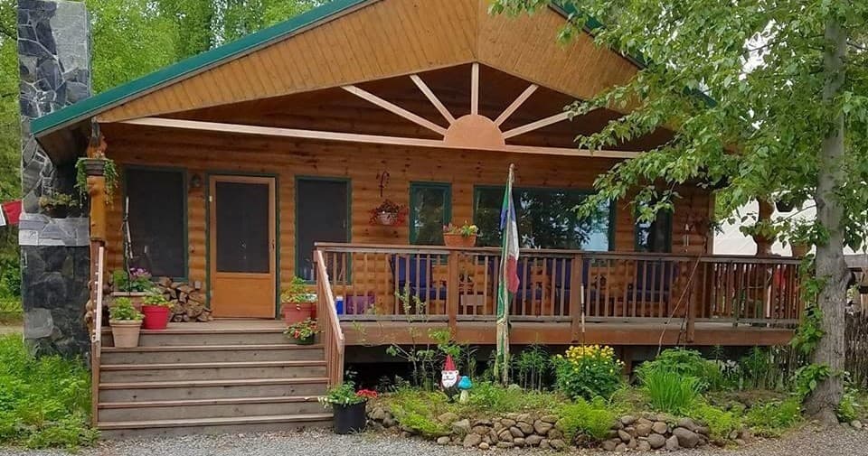 Log cabin lodge front porch with wildflower planters in woods