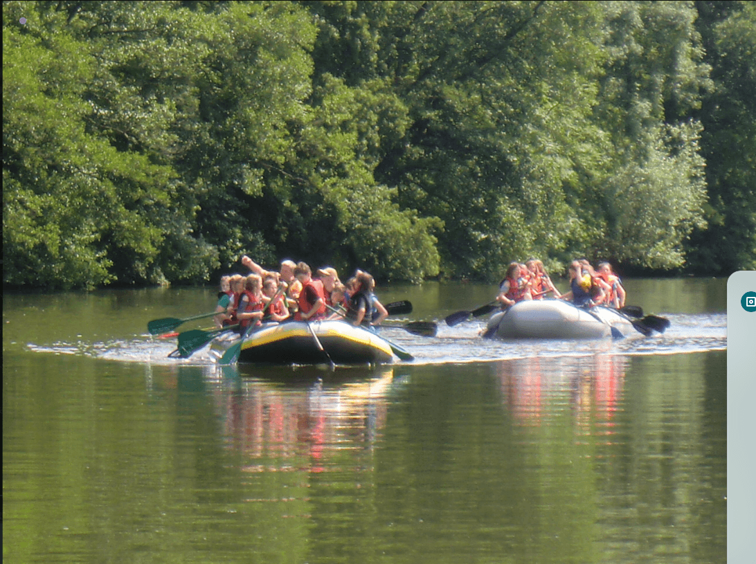 Group rafting down calm river surrounded by green woods