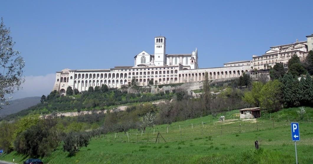 Wide landscape of Assisi basilica and valley under blue sky