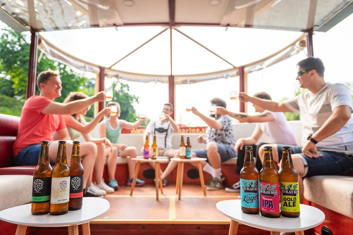 Friends toasting with craft beers on a sunny riverboat deck with bottles