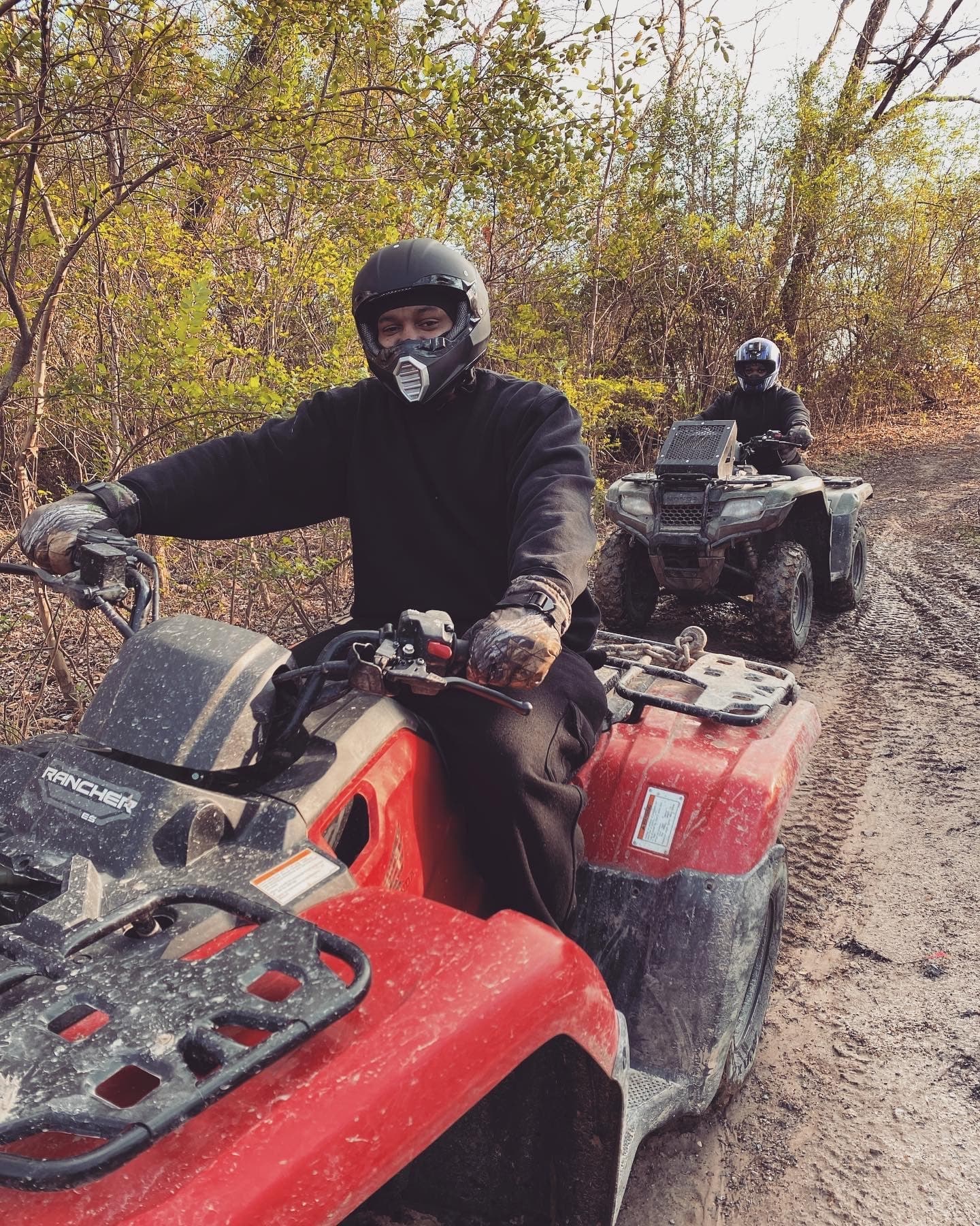 ATV rider leading muddy trail ride through autumn shrubland path