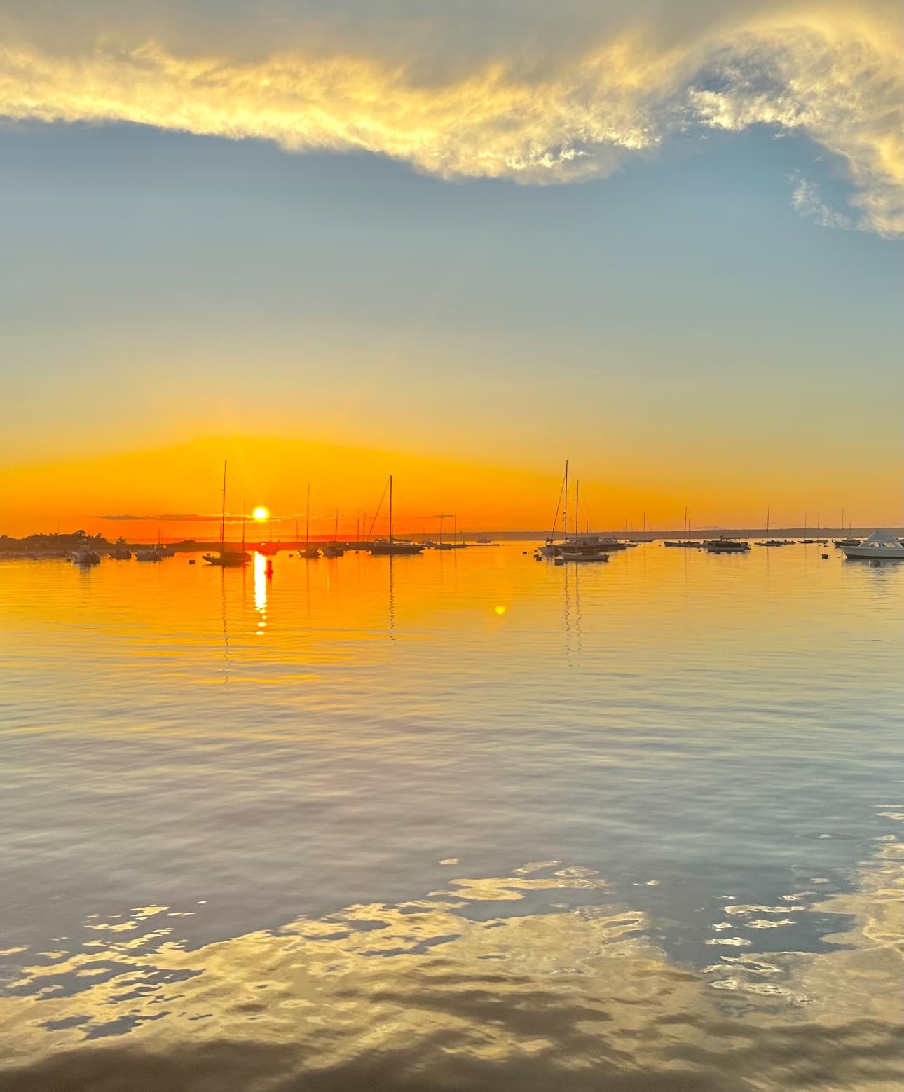Early morning sunrise over tranquil bay with moored boats