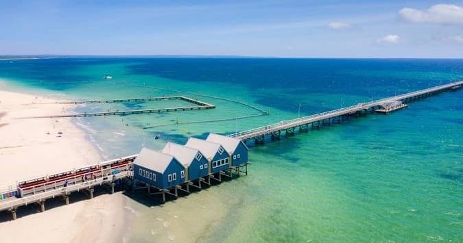 Aerial view of beach and long jetty at sunny coastal pier