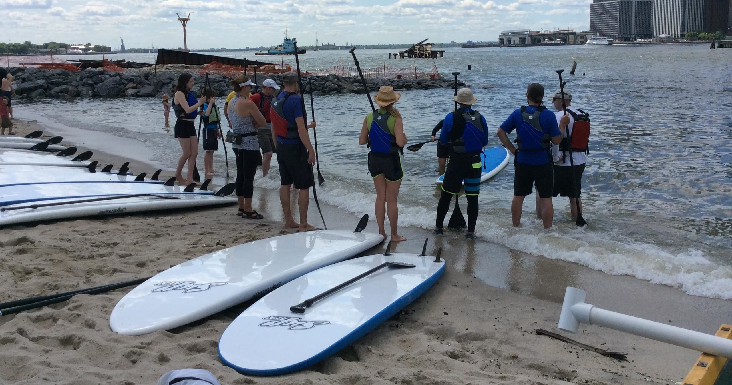Standup paddleboards lined on sandy Brooklyn shoreline