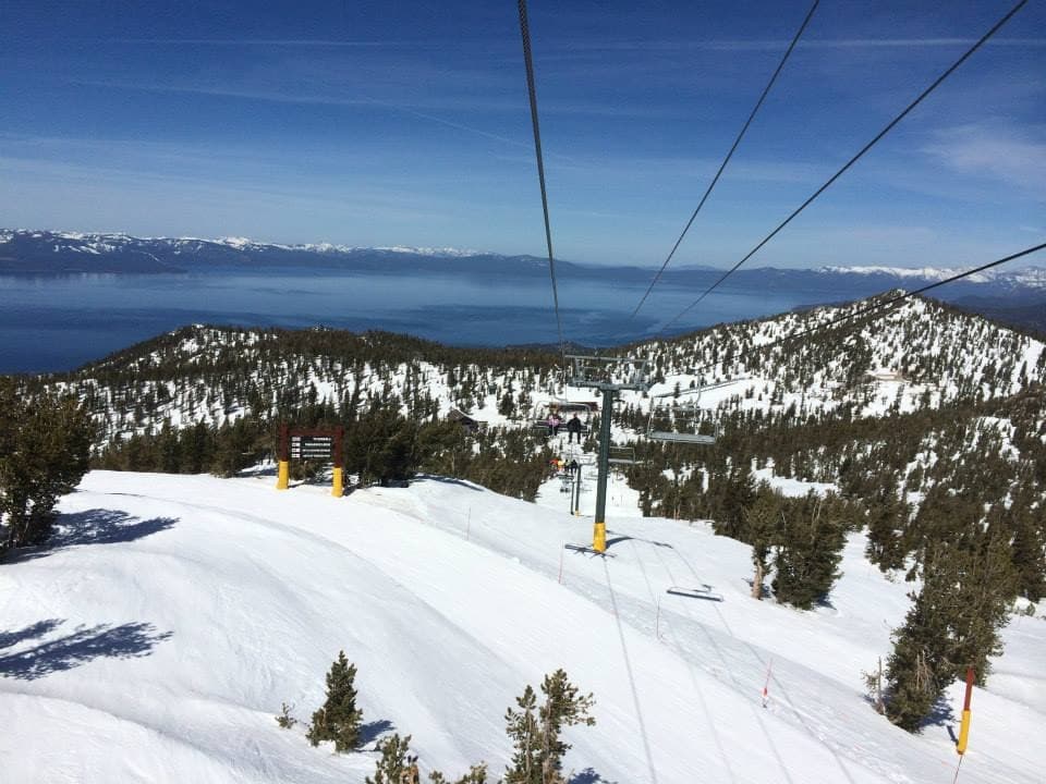 Chairlift and snowy slopes with distant lake vista
