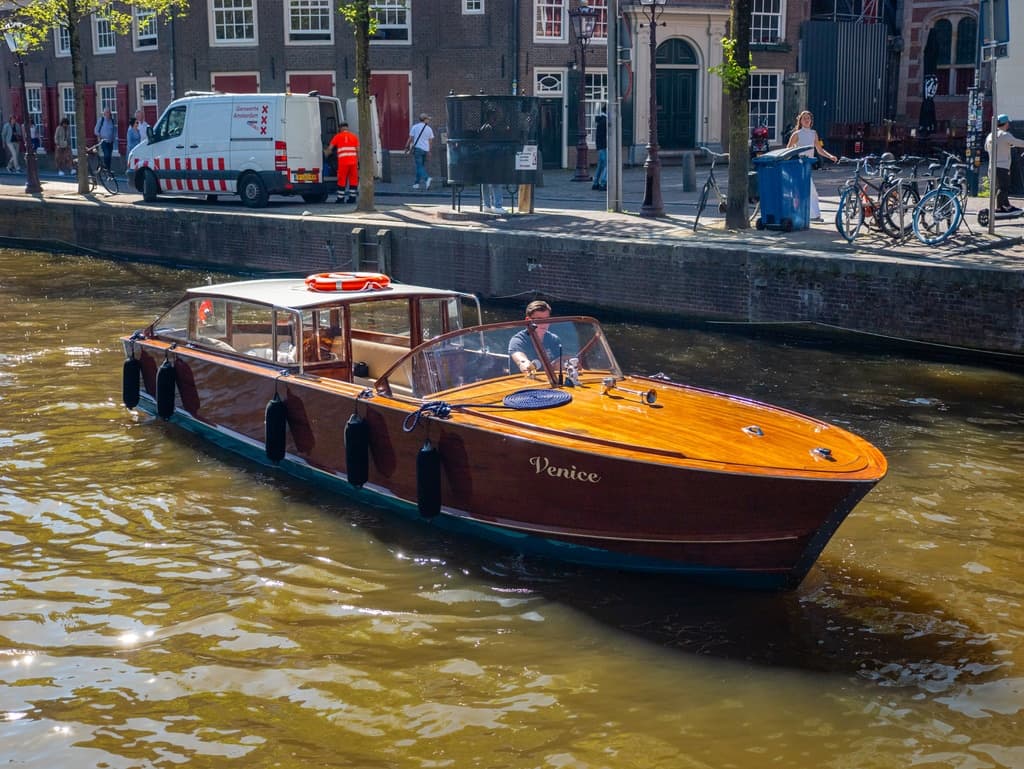 Wooden canal boat cruising Amsterdam canals at sunrise