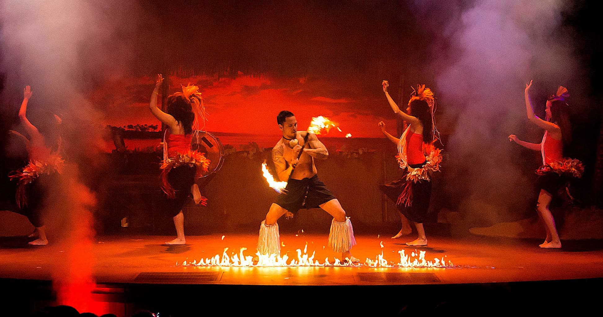 Polynesian fire dancers performing on outdoor beachfront stage