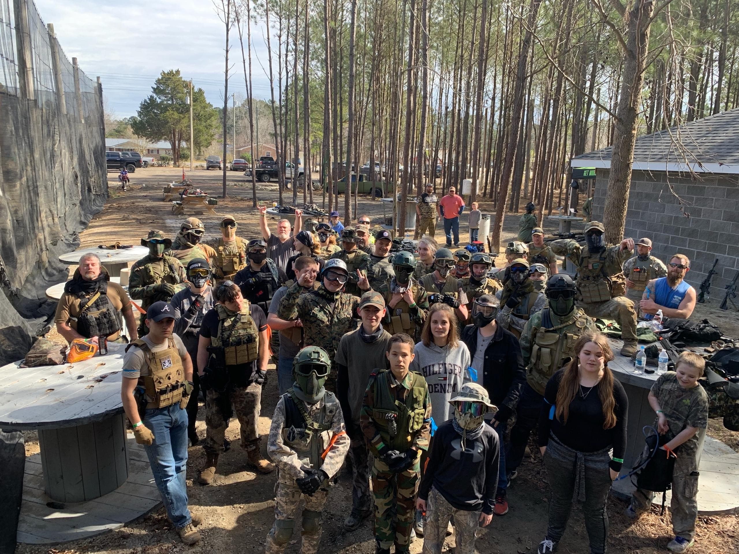 Large paintball group posing on wooded outdoor field at event