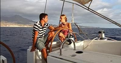 Couple sailing a yacht near coastal mountains, romantic day sail