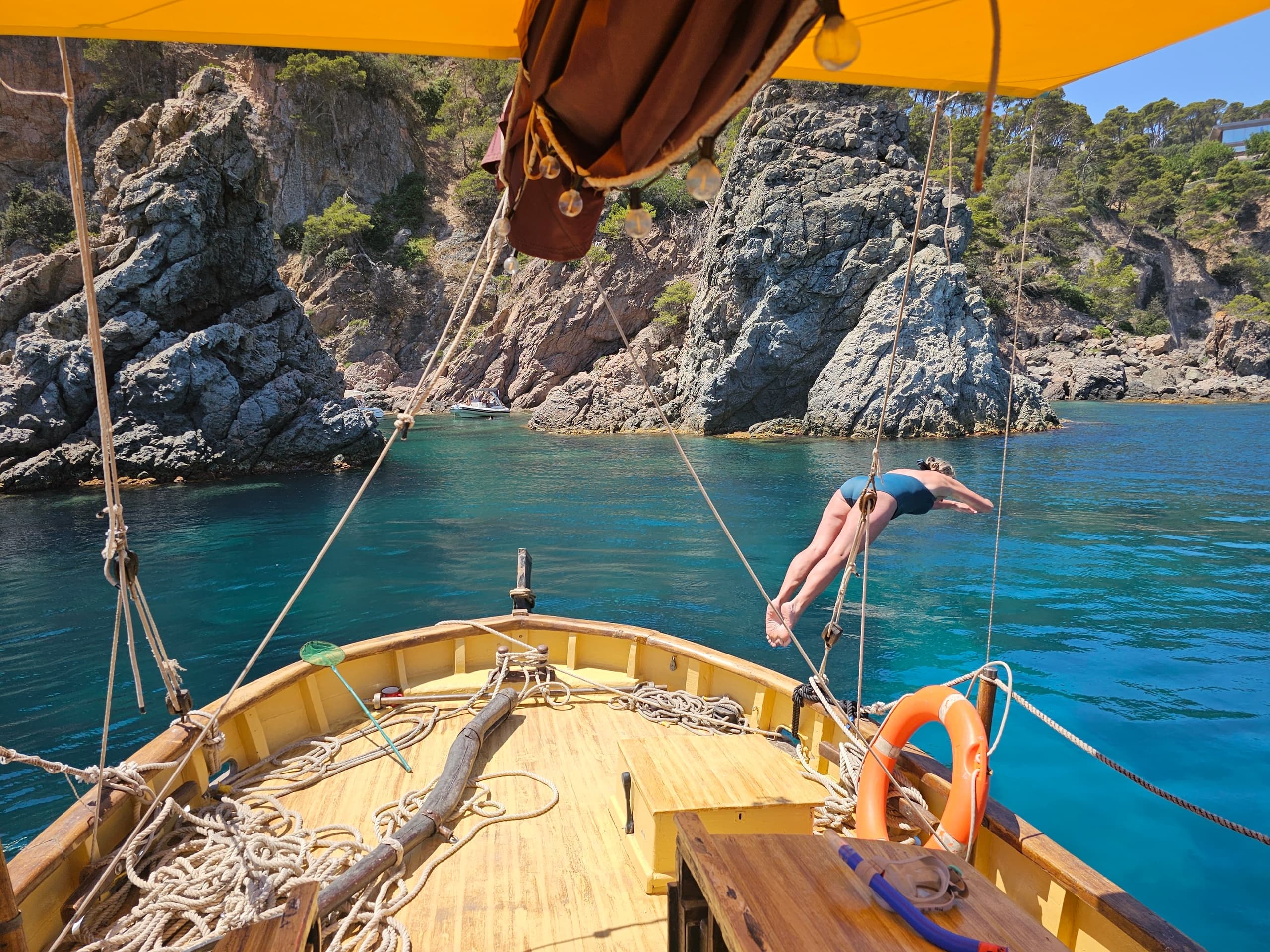 Boat deck view with swimmer diving into turquoise bay