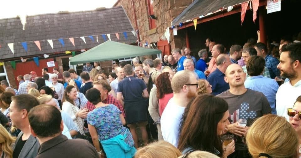 Crowd enjoying outdoor beer festival in sunny village courtyard