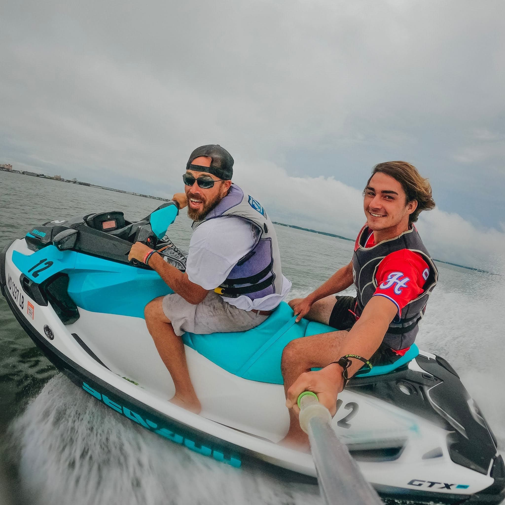 Two riders on jet ski speeding across open coastal waters