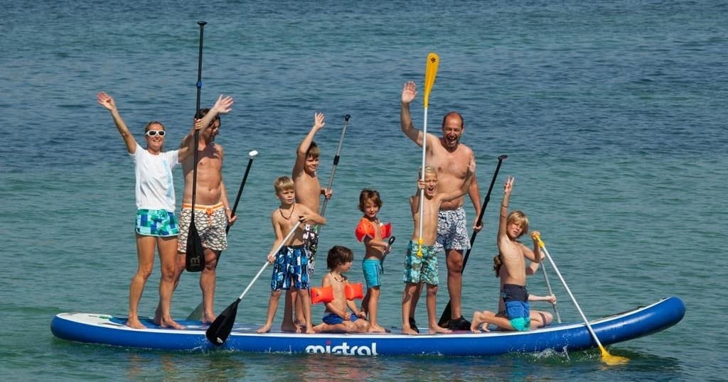 Family and kids paddling together on large inflatable SUP in sea