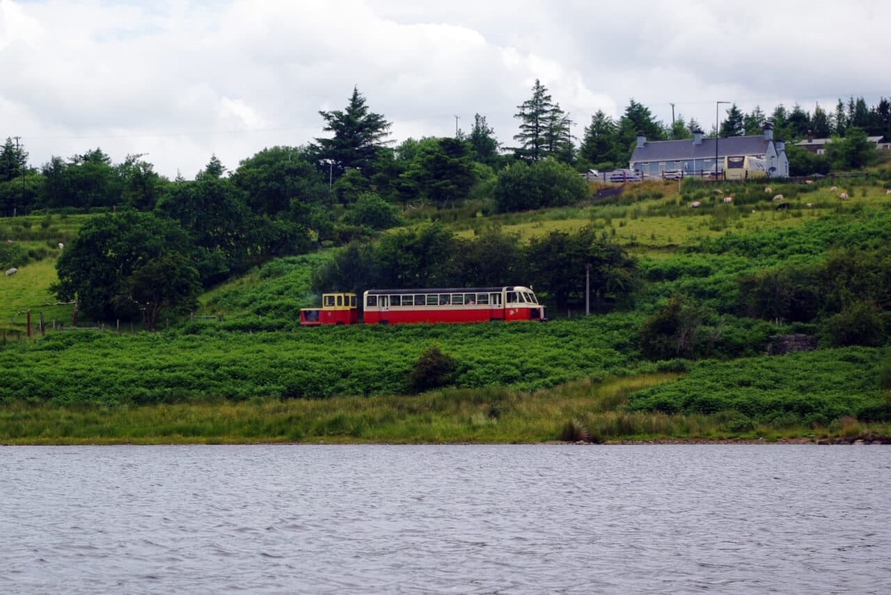 Heritage train traveling along lakeside in rugged hills