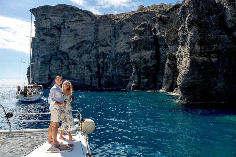 Couple on yacht near dramatic coastal cliffs and turquoise water