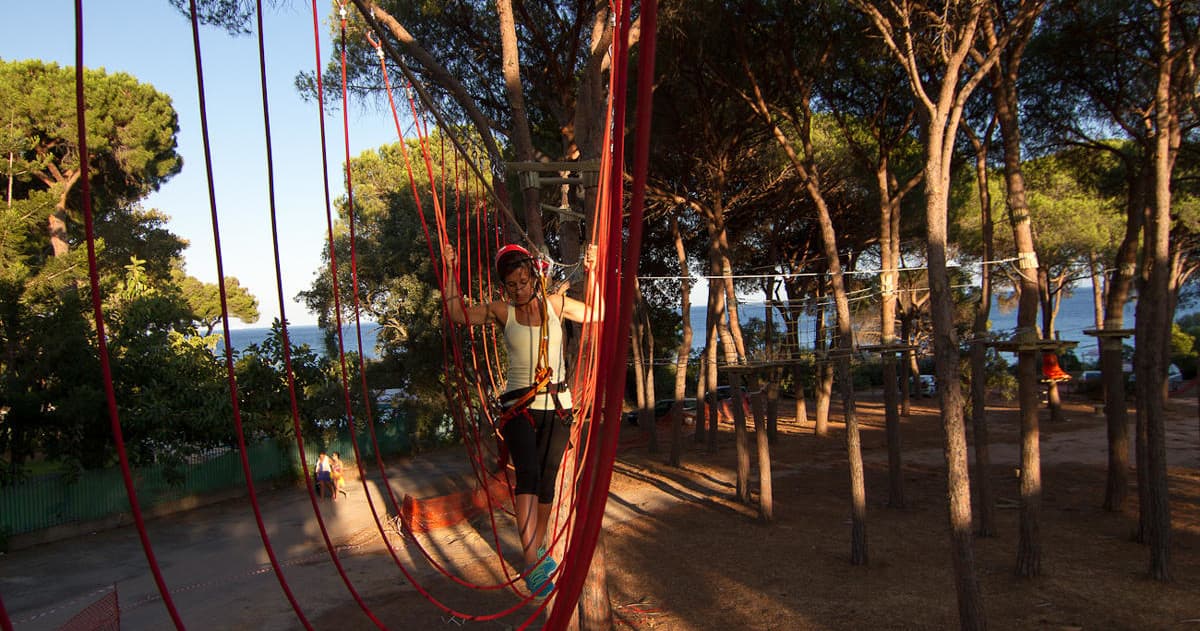 Adventure ropes course with red safety nets in shaded forest