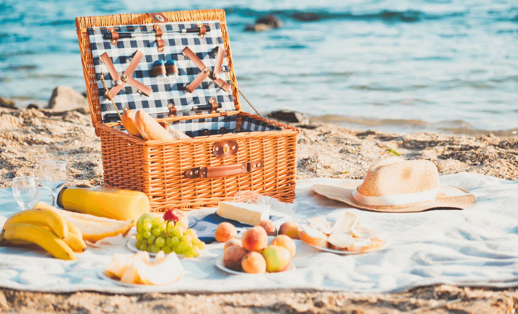 Beach picnic basket setup on sandy shore by calm sea