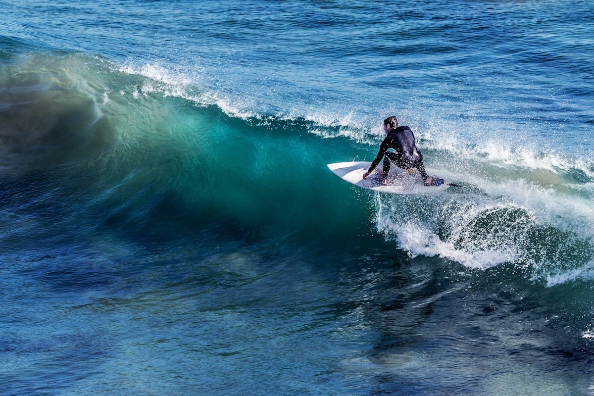 Surfer carving inside a teal ocean wave on an energetic swell