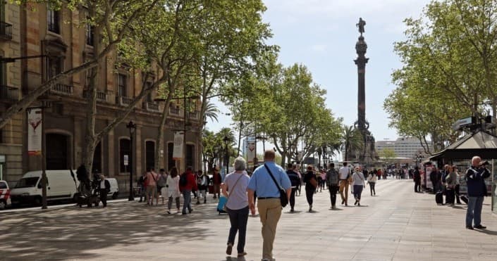 Pedestrians strolling La Rambla boulevard with Columbus monument