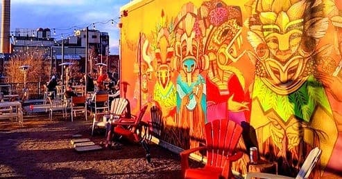 Colorful street mural with outdoor seating at urban patio