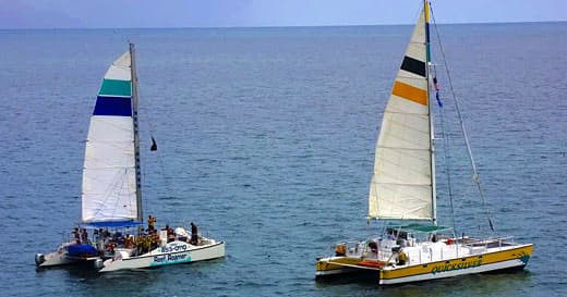 Twin catamarans sailing together on open blue ocean tour