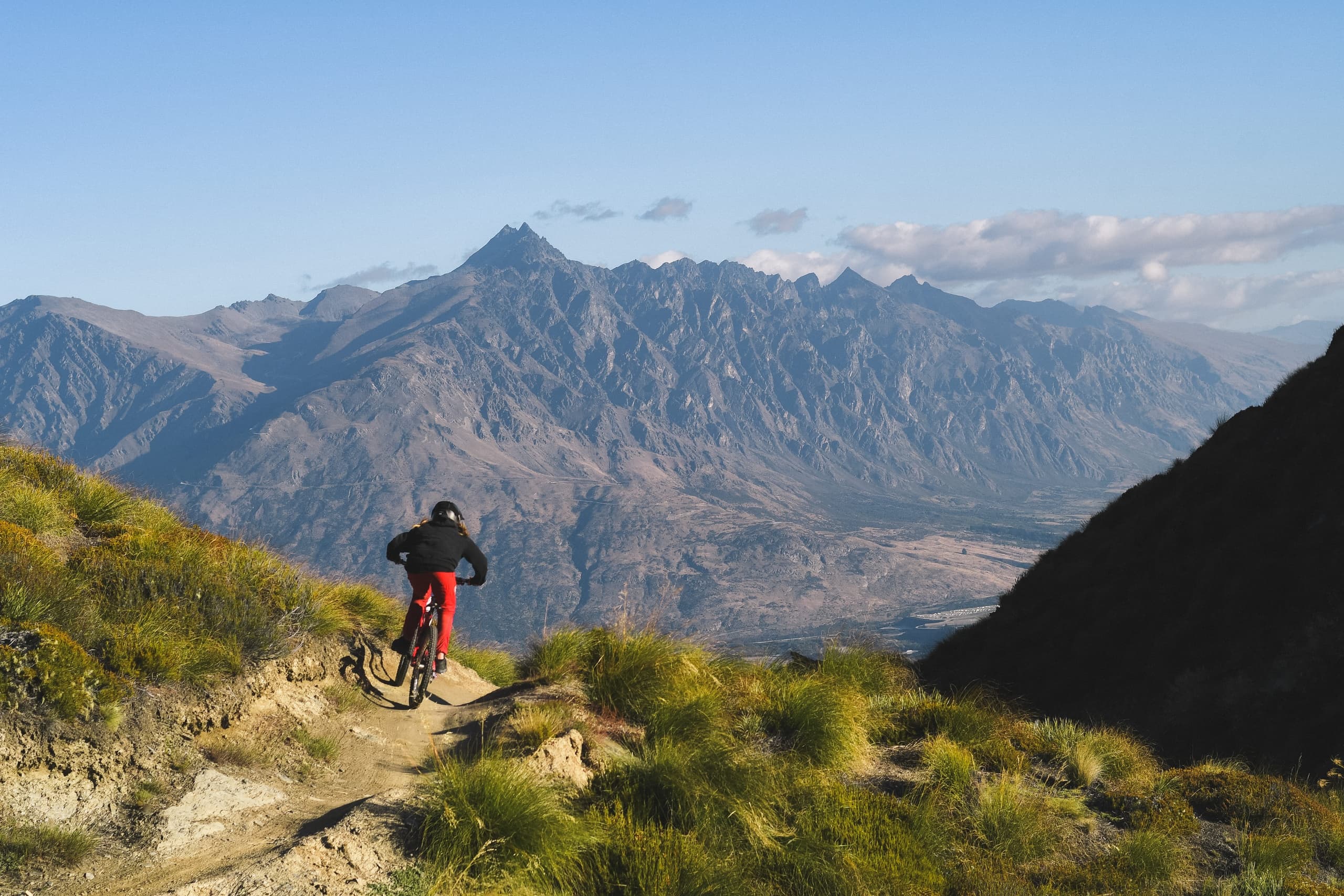 Solo rider on ridge trail with sweeping mountain views New Zealand