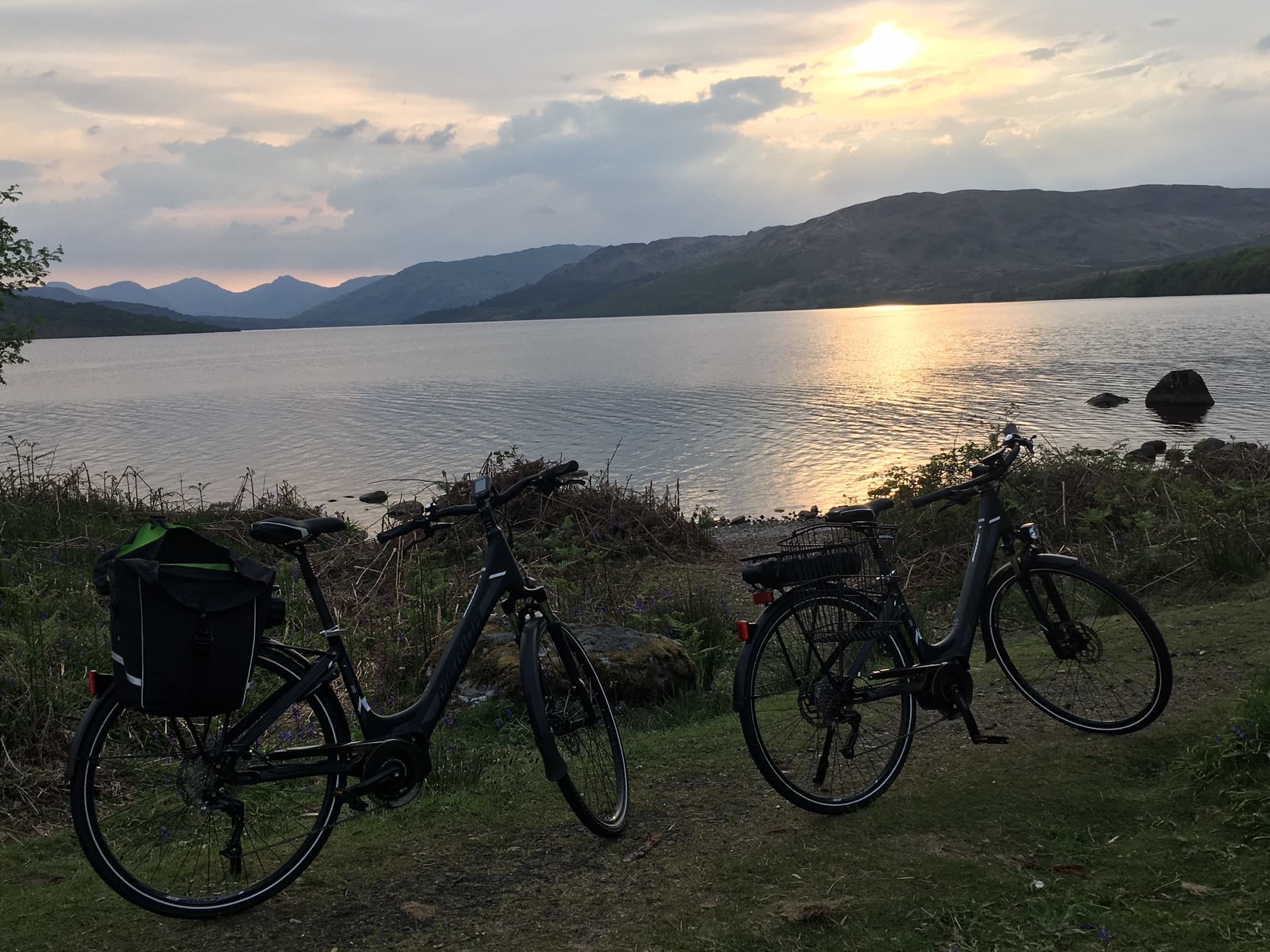 Two touring bikes parked by Trossachs loch at golden sunset