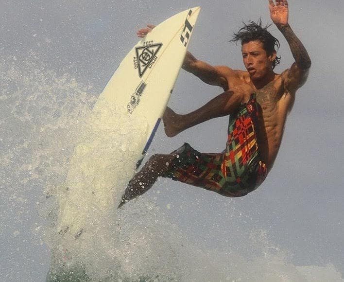 Surfer performing aerial maneuver over ocean wave at beach