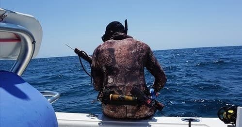 Spearfisher sitting on boat in open ocean during hunt