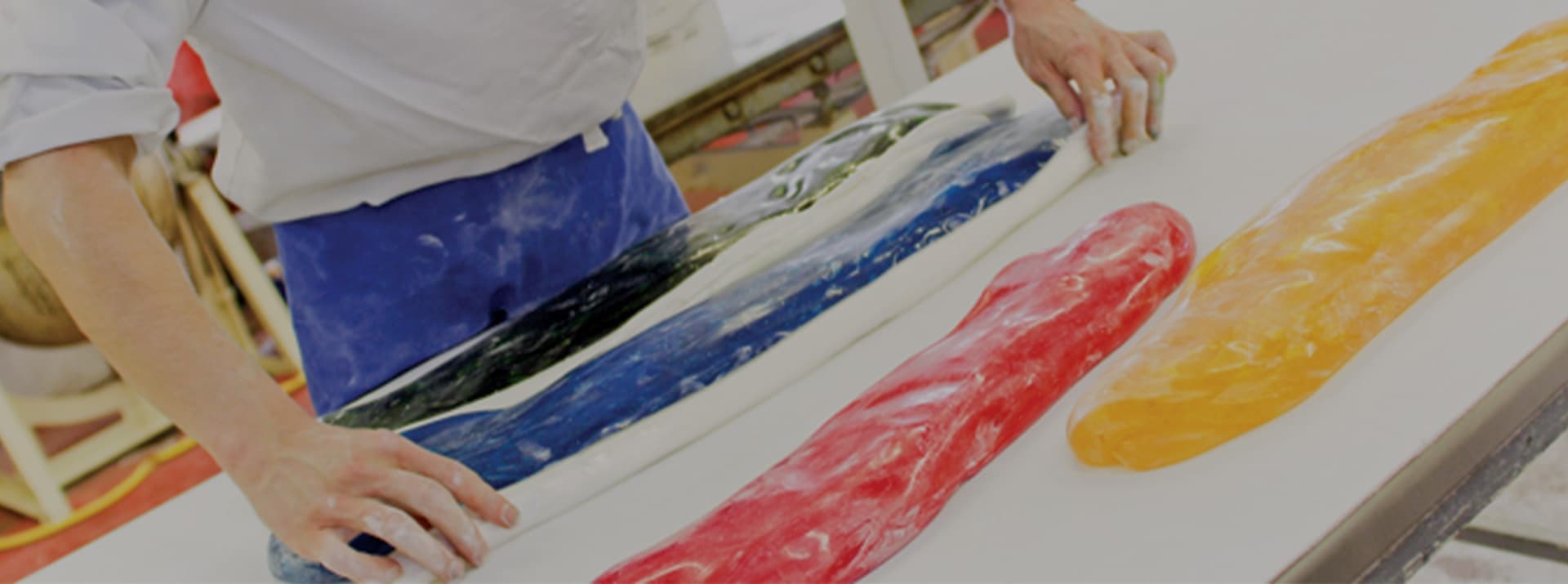 Confectioner rolling colorful candy taffy in a candy workshop