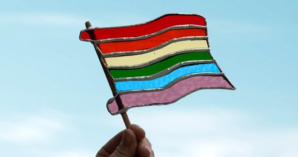 Hand-painted rainbow flag fluttering against blue sky outdoors