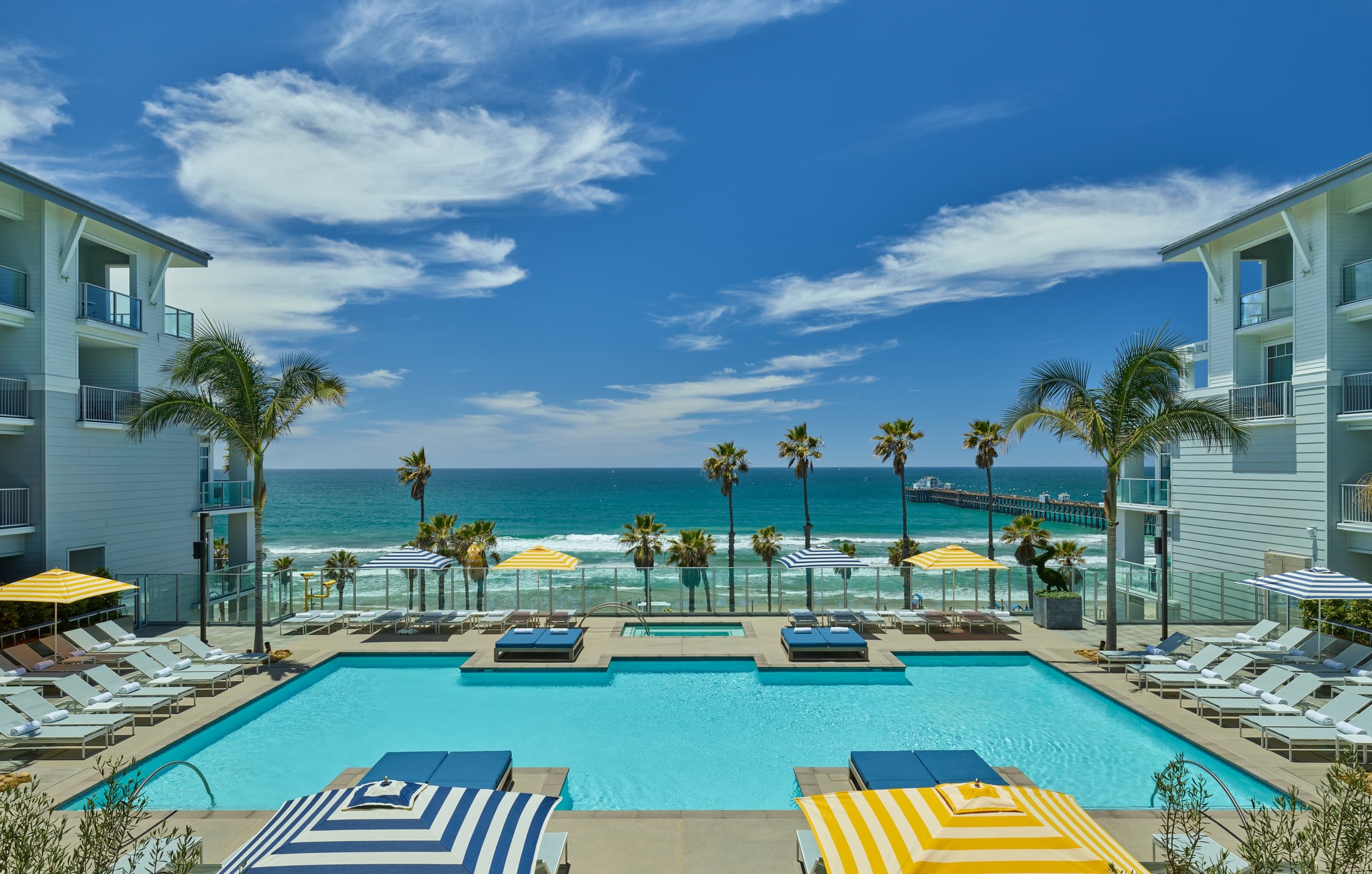 Oceanfront resort poolside loungers with palm-lined view