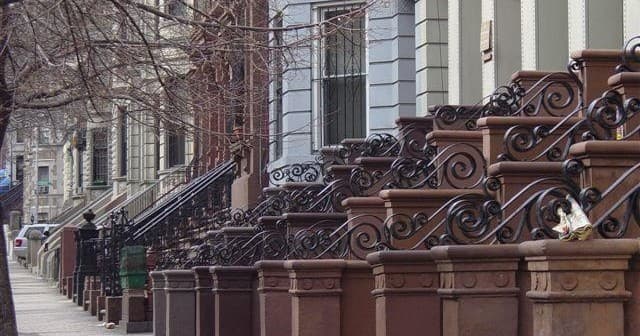 Historic brownstone facades with ornate iron railings, city stroll