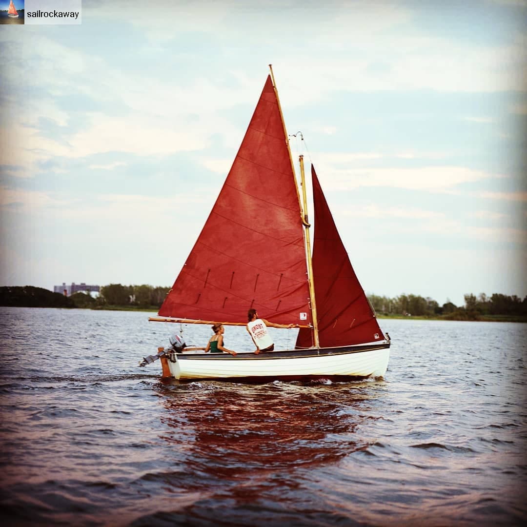 Classic red-sailed small boat cruising calm harbor waters