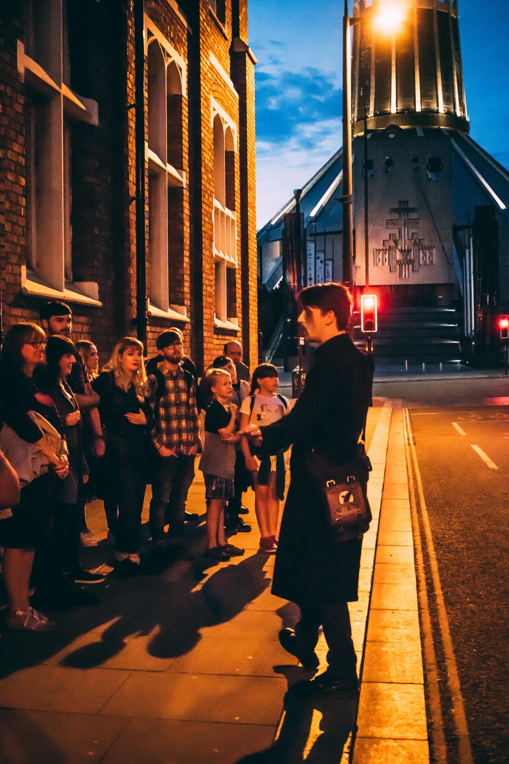 Tour guide leading ghost walk on Liverpool street at dusk