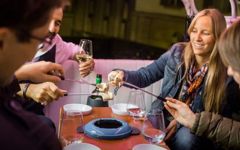 Friends sharing indoor fondue dinner at cozy restaurant table