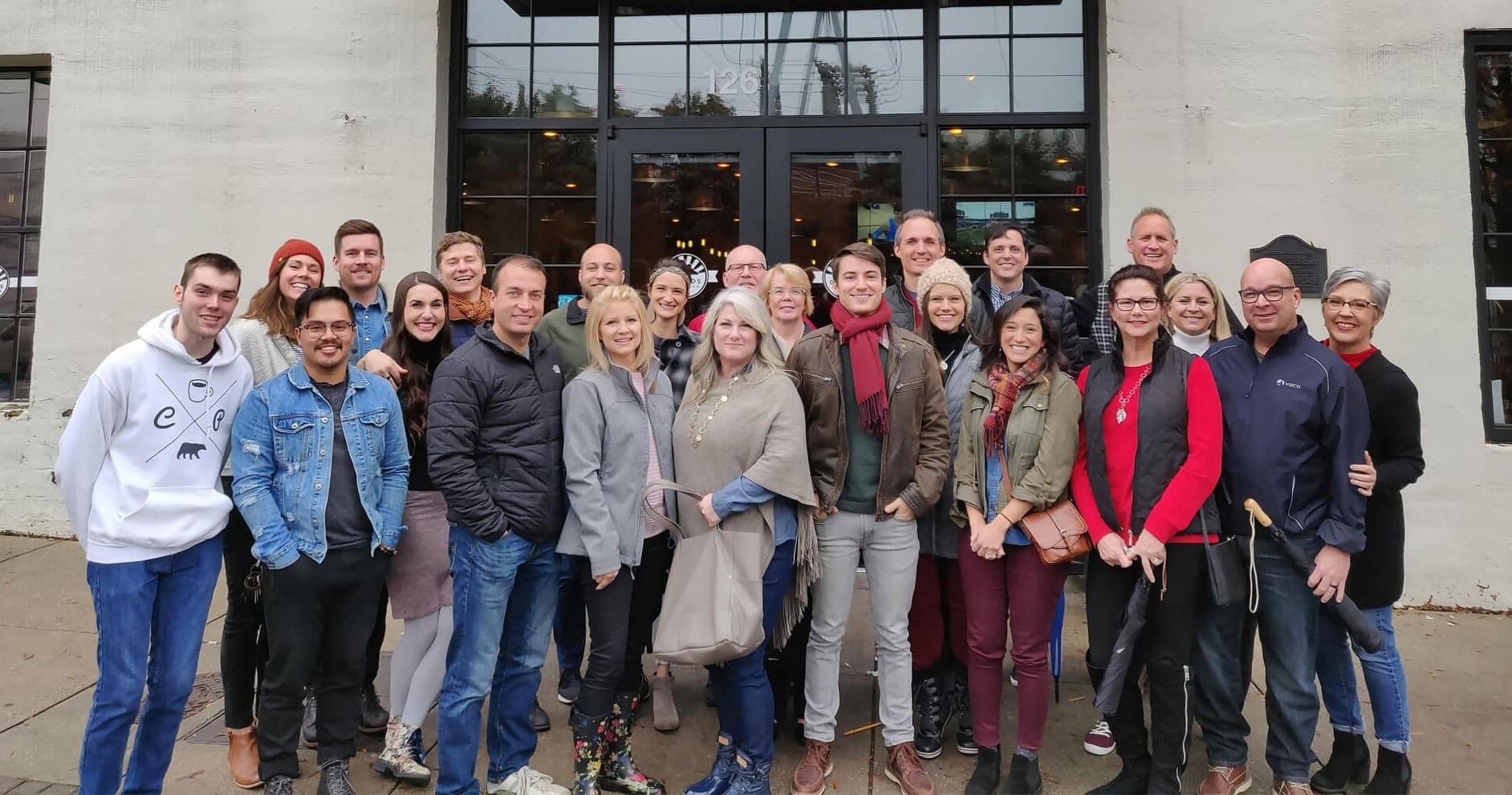 Large walking tour group posing outside museum entrance on sidewalk