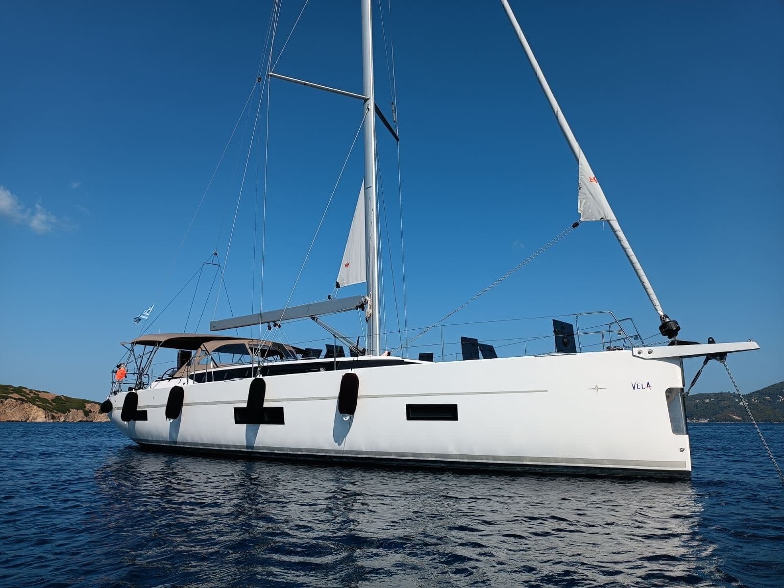 White sailing yacht anchored in deep blue sea under clear sky