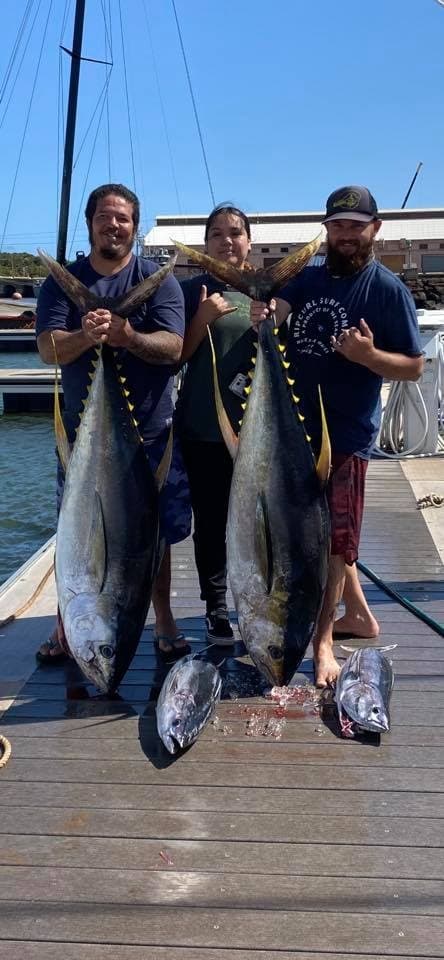 Three anglers posing with yellowfin tuna on marina dock