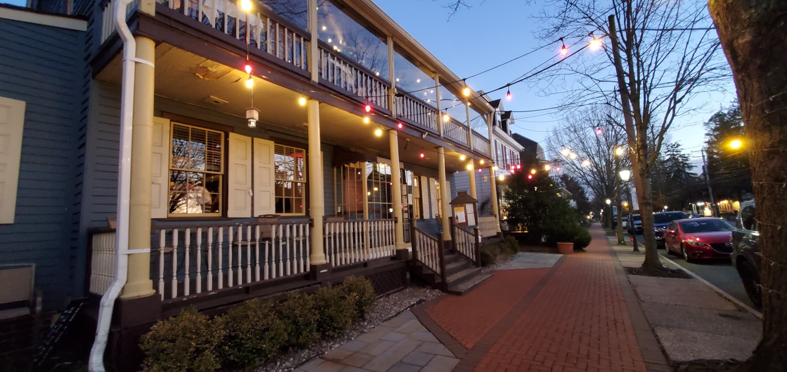 Evening streetscape with lit shops and sidewalk dining