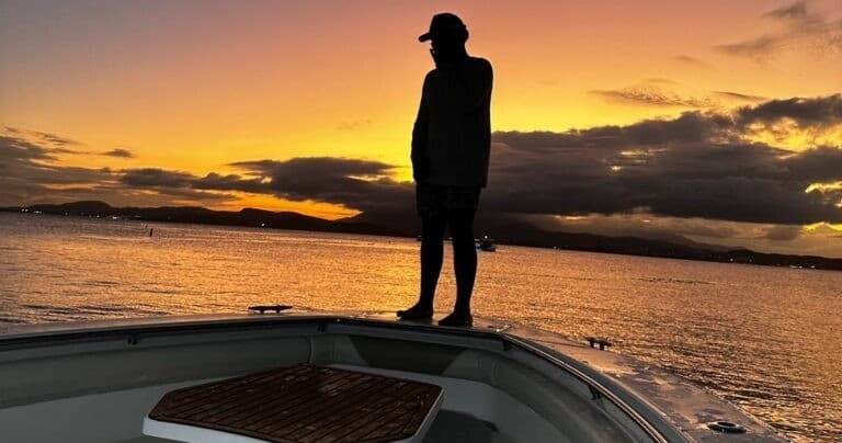 Silhouette on boat bow at sunset over open ocean cruise