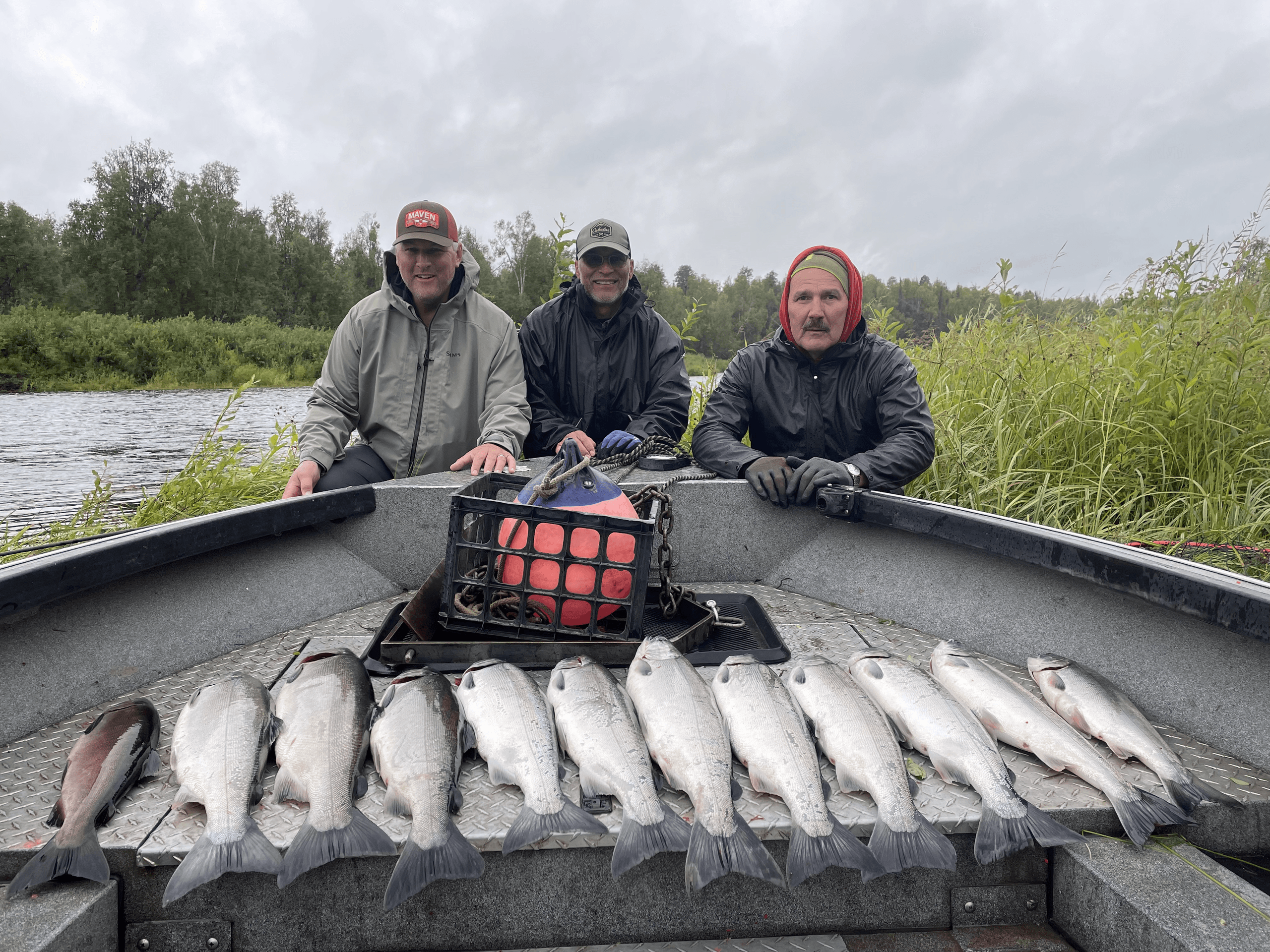Three anglers in boat with lined catch of trout on river trip