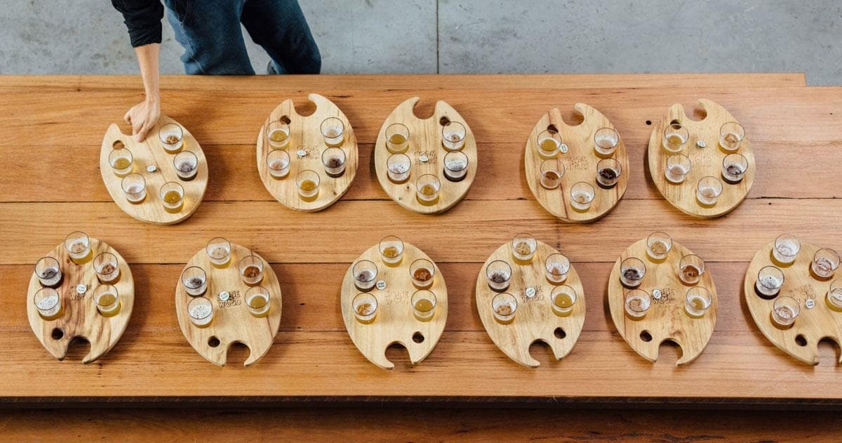 Multiple beer tasting paddles displayed on long wooden table, group tasting