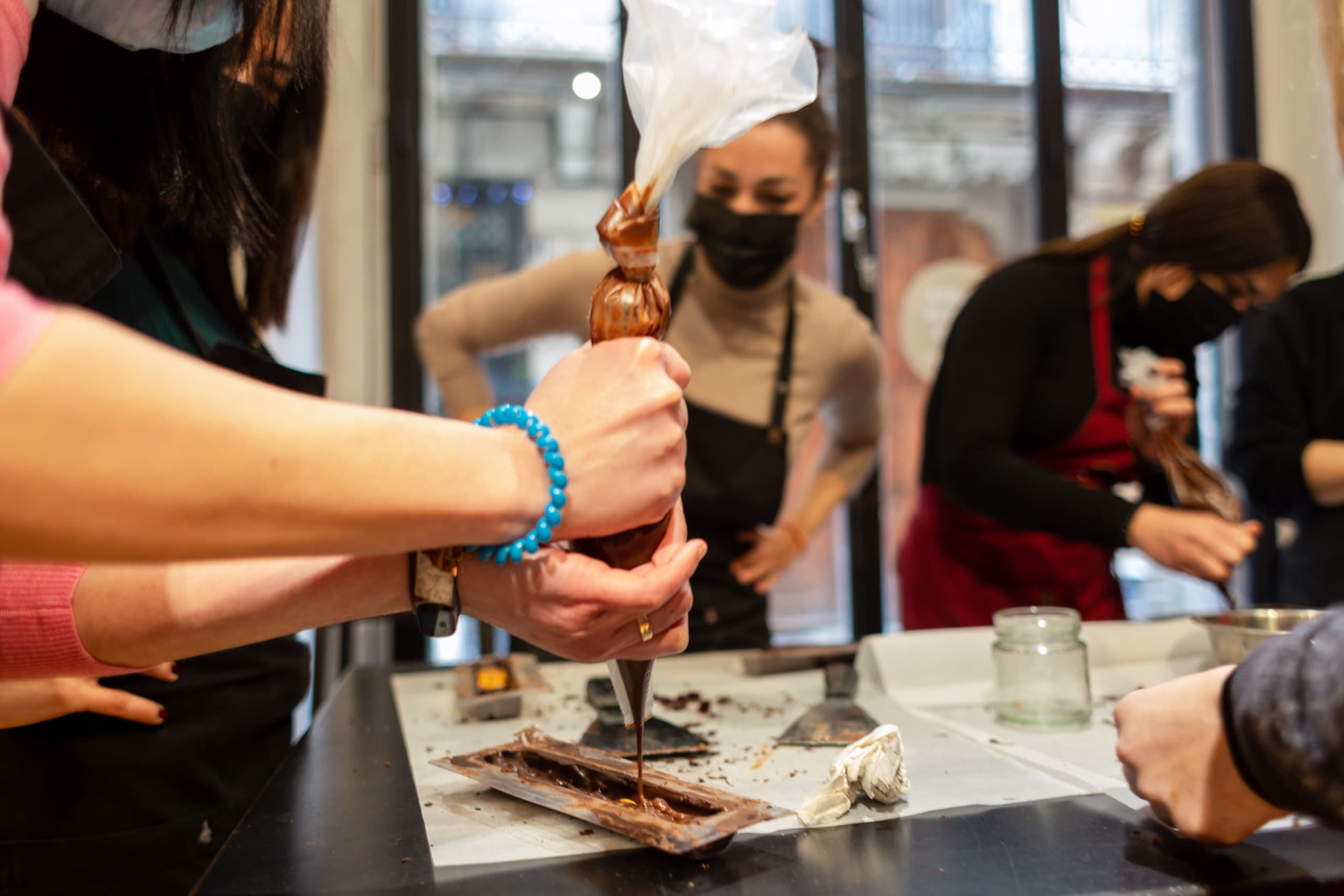 Hands piping chocolate bonbons during indoor candy workshop