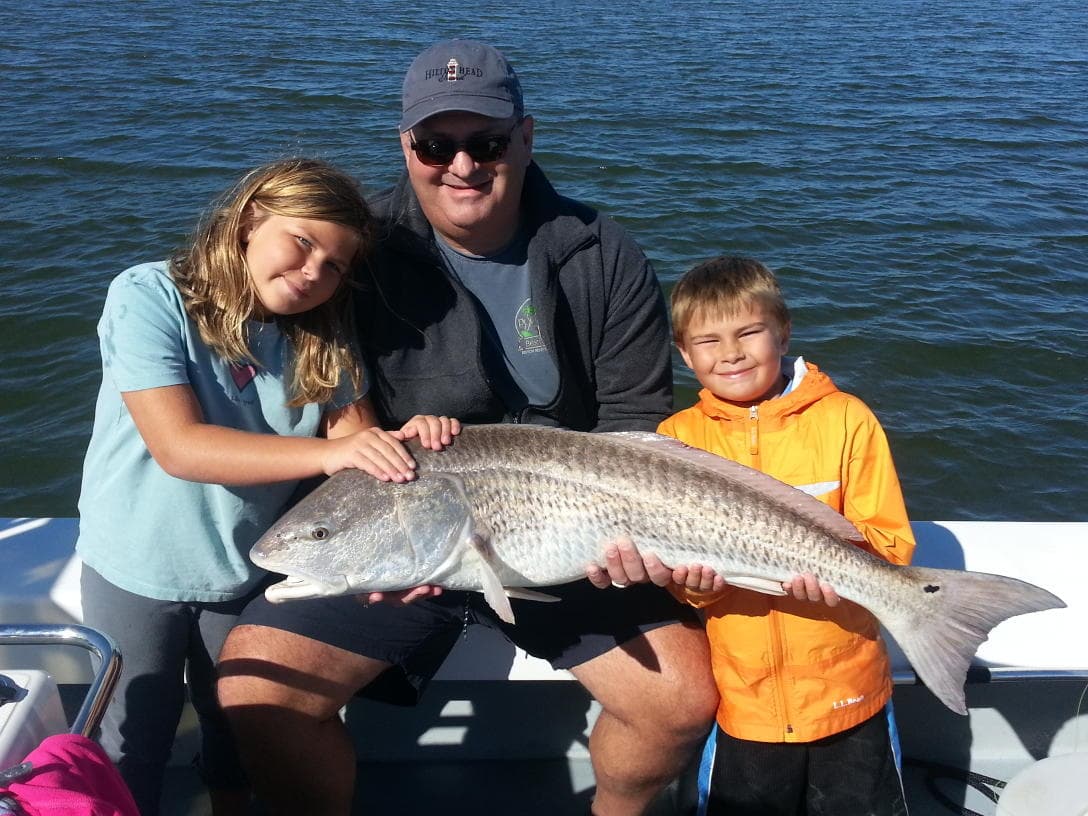 Family holding trophy fish on fishing charter in calm sea