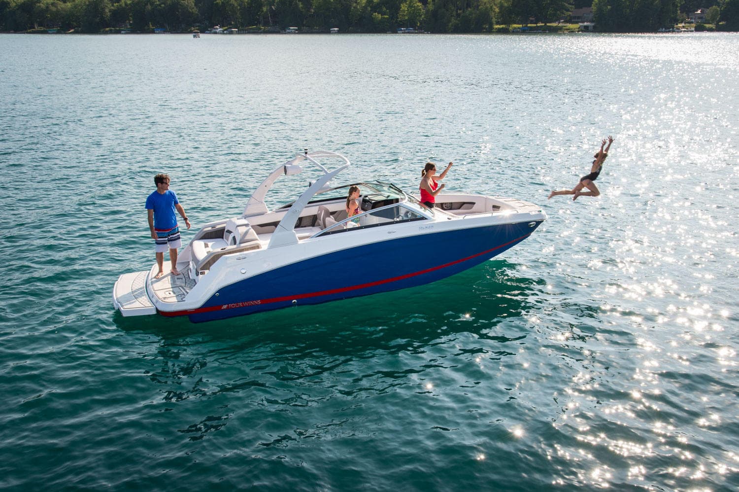 Speedboat pulling waterskier across bright mountain-blue lake