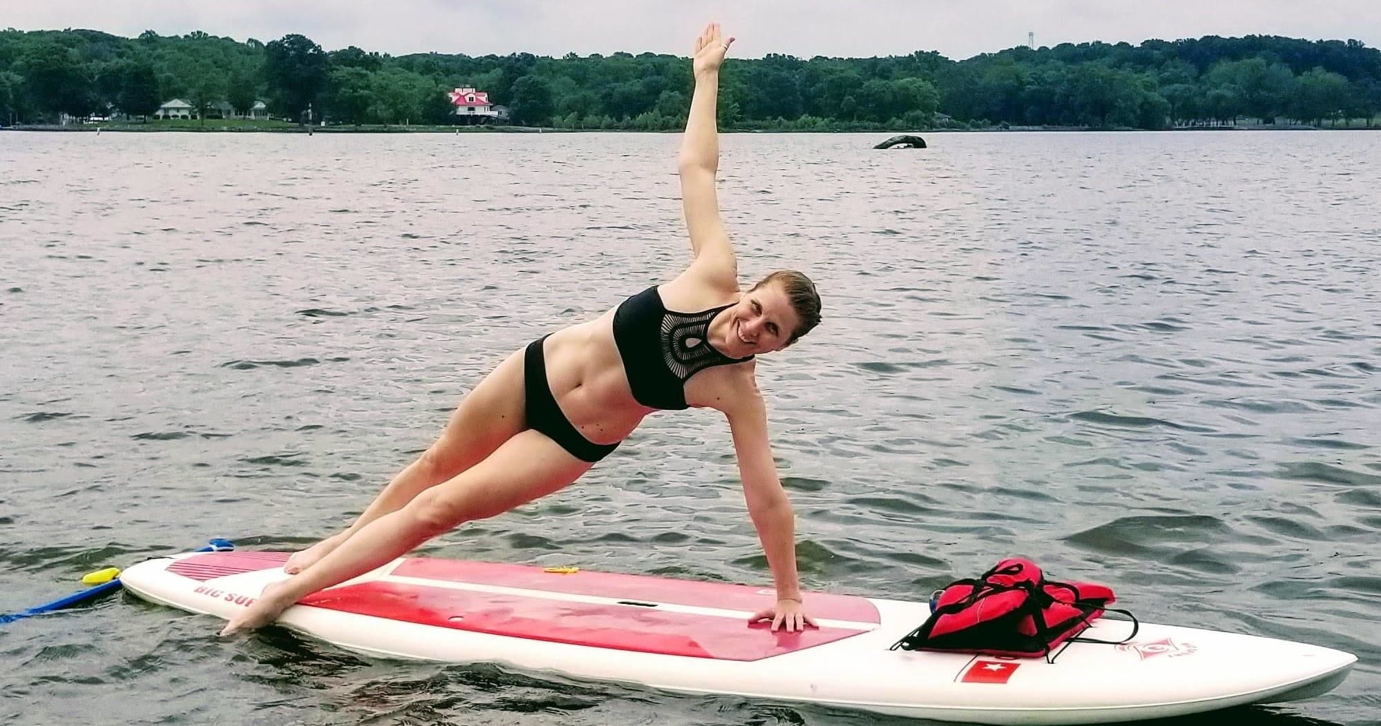 Paddleboard yoga side-plank on lake, fitness on SUP